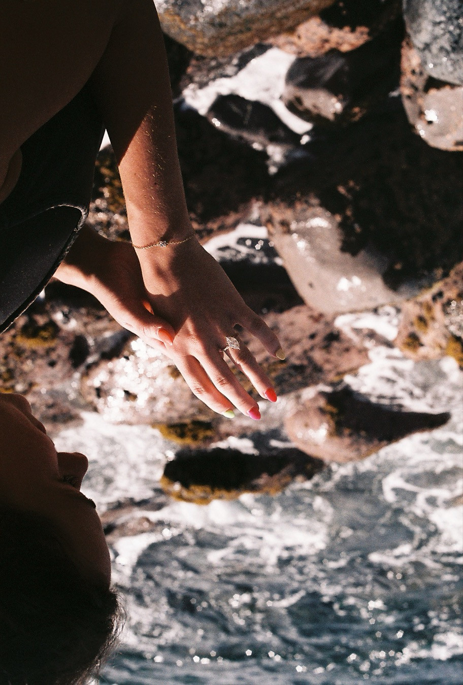 35mm film photograph of an engagement ring held over the sea