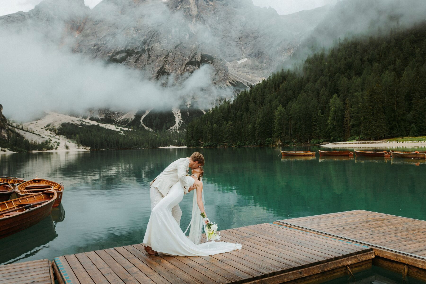 A couple on a jetty by an alpine lake on their elopement day
